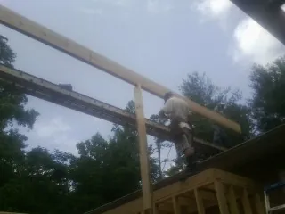 Carpenter setting a ridge beam over a new addition frame — Ice Dam Removal by Roofing Brothers in Wells Bridge