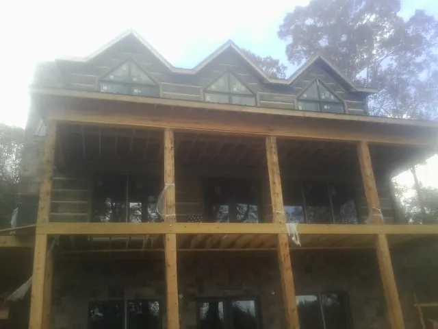 Dormers and porch framing on a large log home under construction — Roof Coating work by our crew in Wells Bridge
