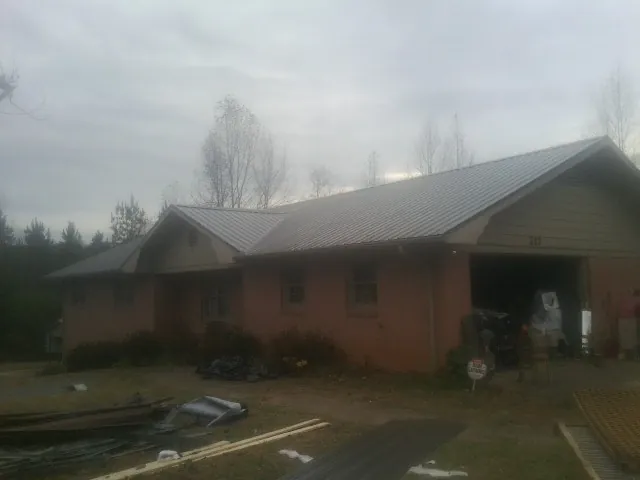 Gray metal roof on a stucco house with an attached garage in Wells Bridge