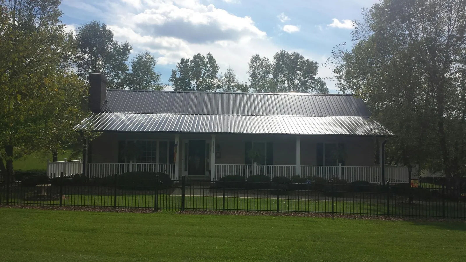 Gray metal roof on a brick ranch with a full width front porch — Gutter Guard Installation work by our crew in Wells Bridge