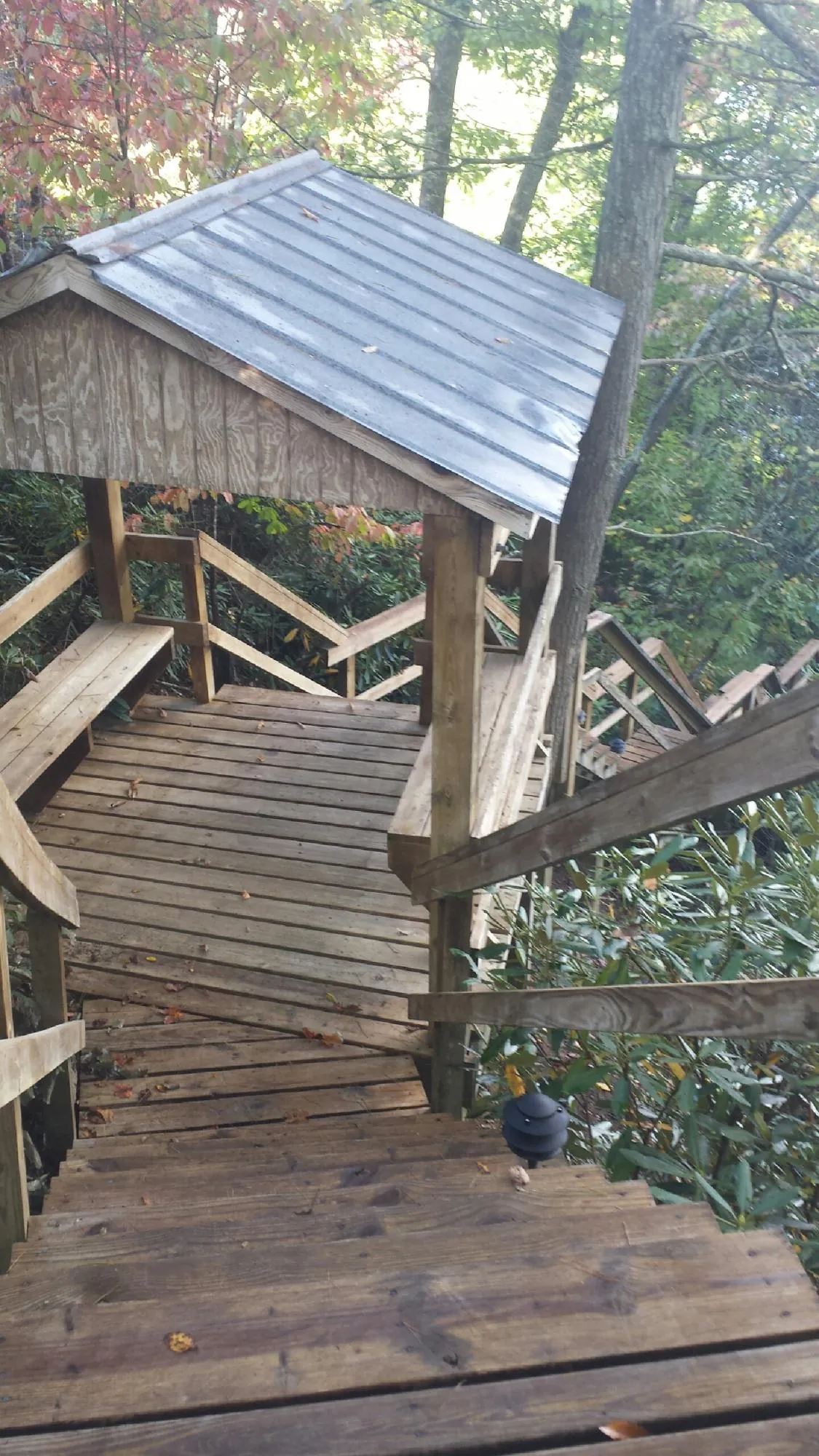 Metal roofed shelter over wooden steps on a wooded walkway — Skylight Repair & Installation work by our crew in Wells Bridge