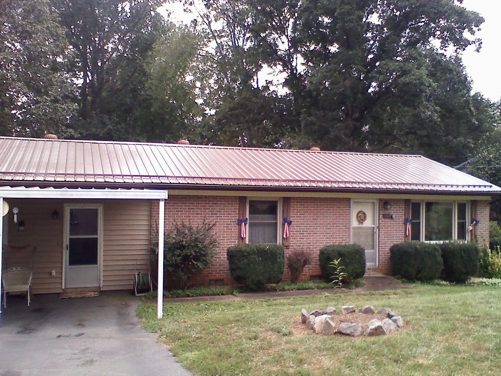 Bronze metal roof and carport on a brick ranch home — Roof Repair work by our crew in Wells Bridge